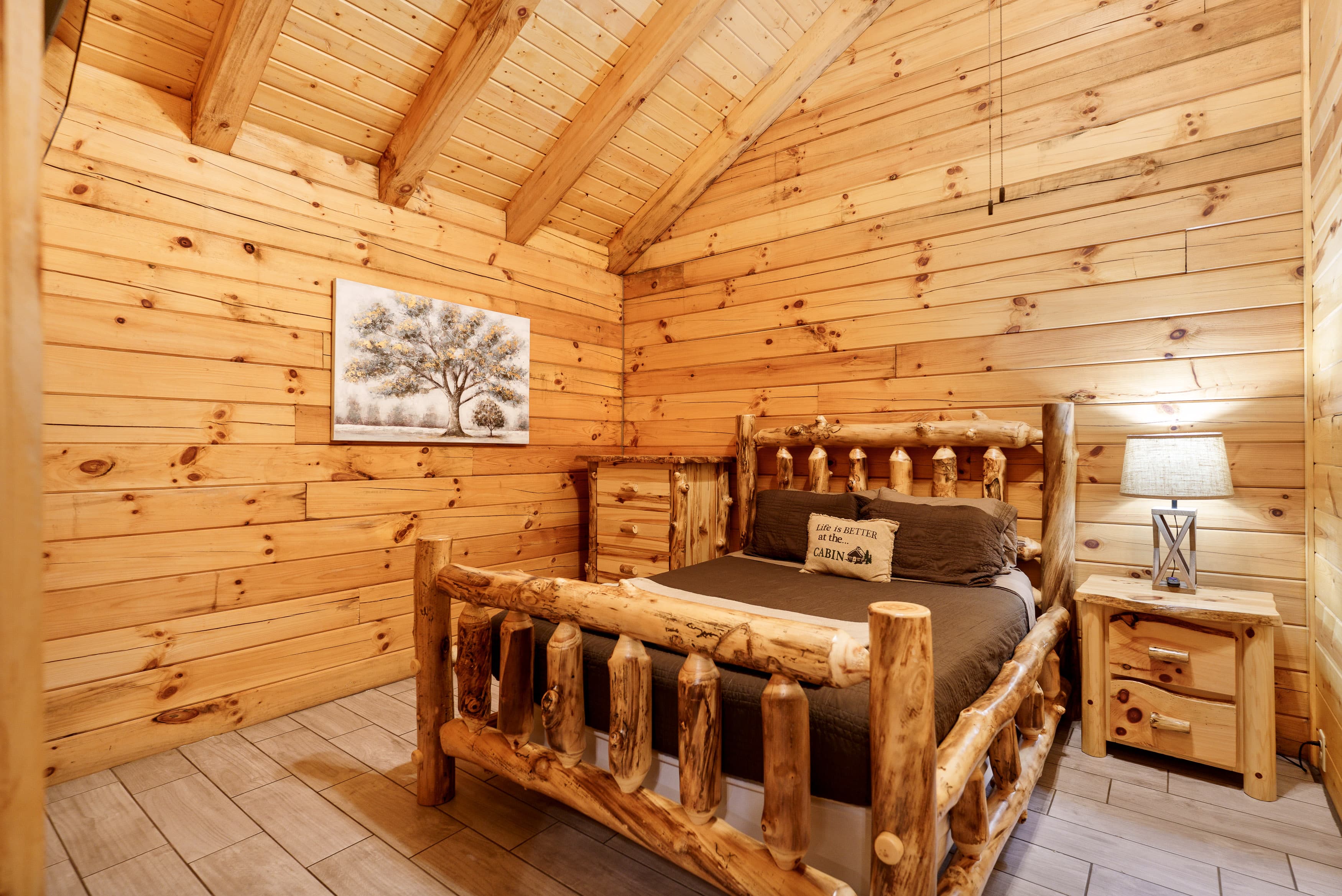 Cozy wooden bedroom featuring a log-style bed, nightstand, and artwork on the wall.