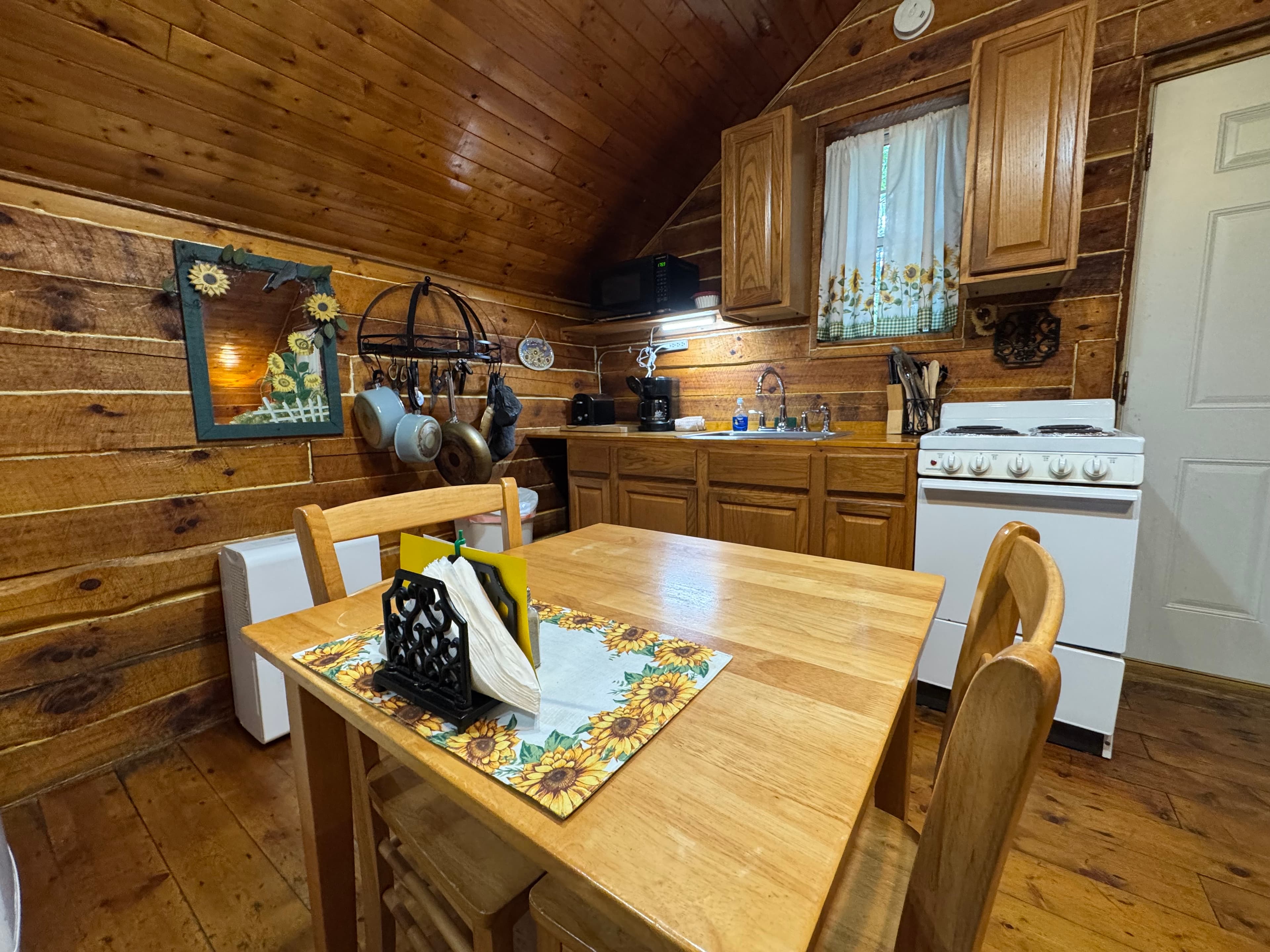Cozy kitchen with wooden walls, a dining table, and a gas stove.