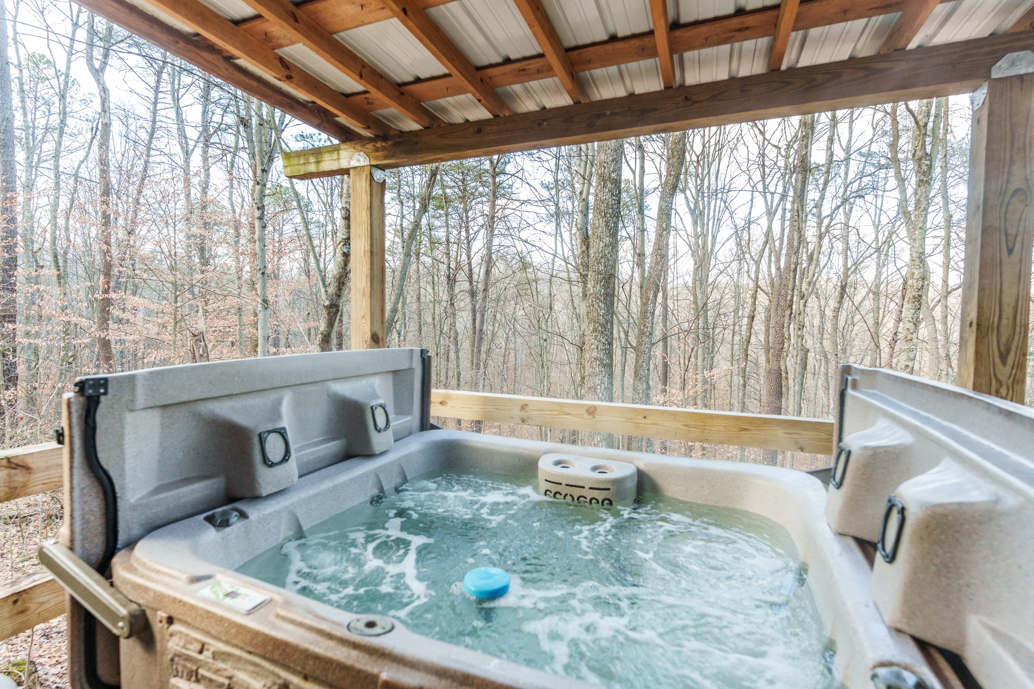 A hot tub filled with bubbling water overlooks a serene forest landscape.