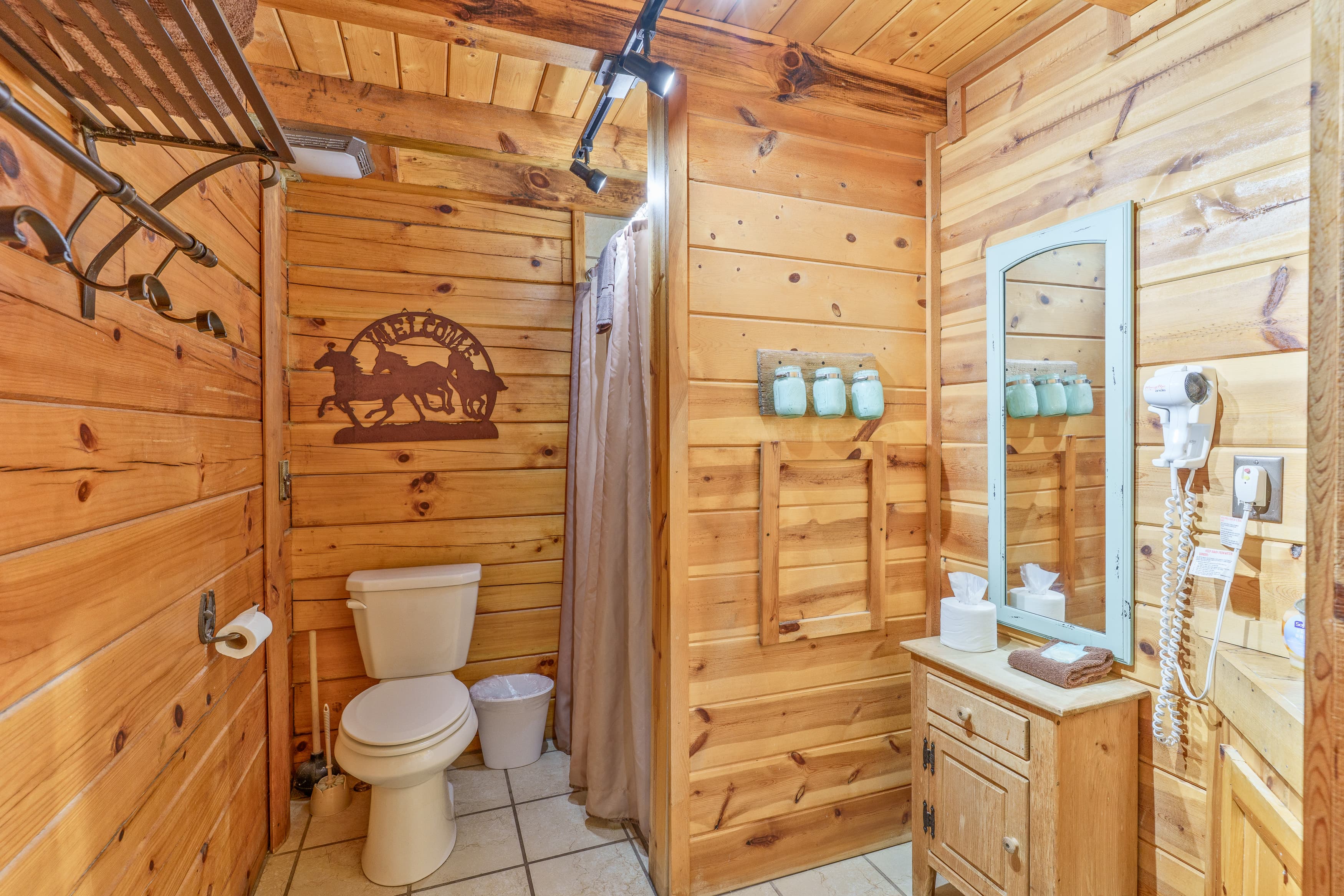 Cozy wooden bathroom with a toilet, shower, mirror, and rustic decor.