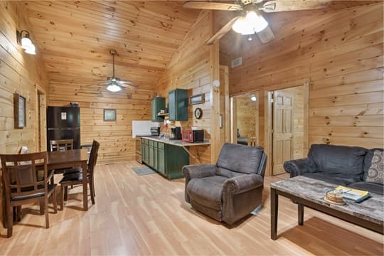Cozy wooden interior featuring a living area, dining table, and kitchen appliances.