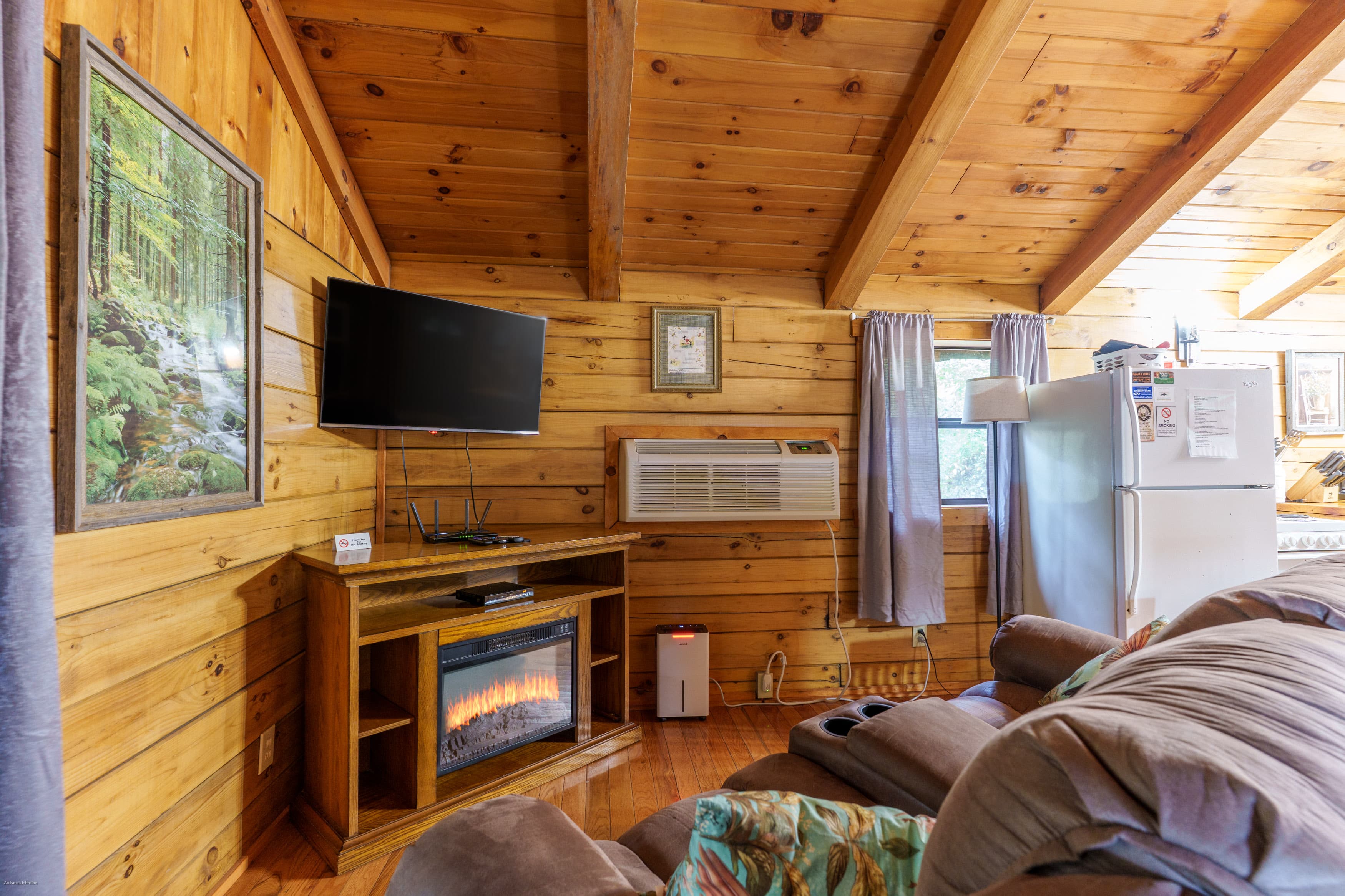 Cozy living room with wooden walls, a television, and an electric fireplace.