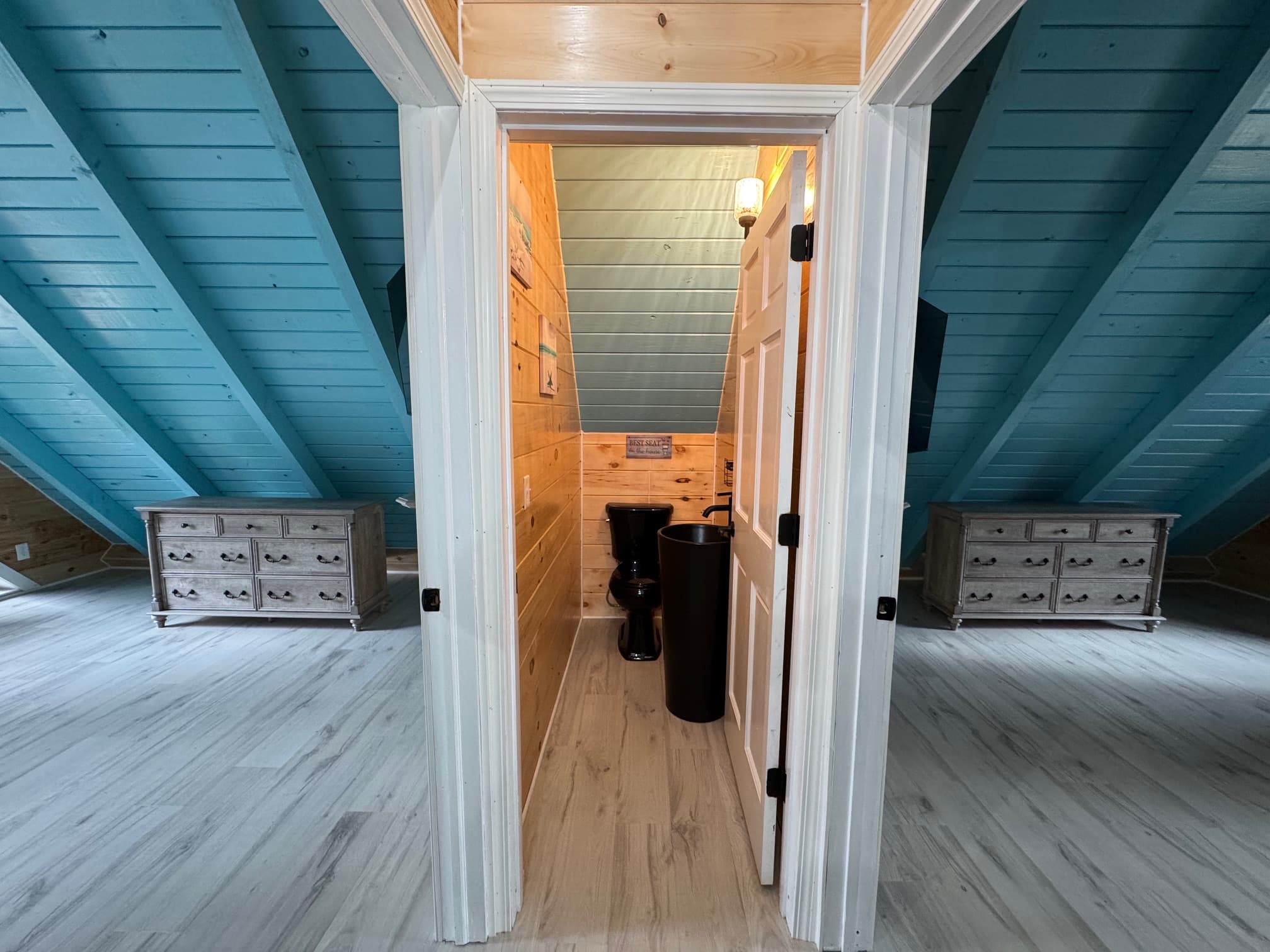 A modern, spacious attic bathroom with wooden walls and a blue ceiling.