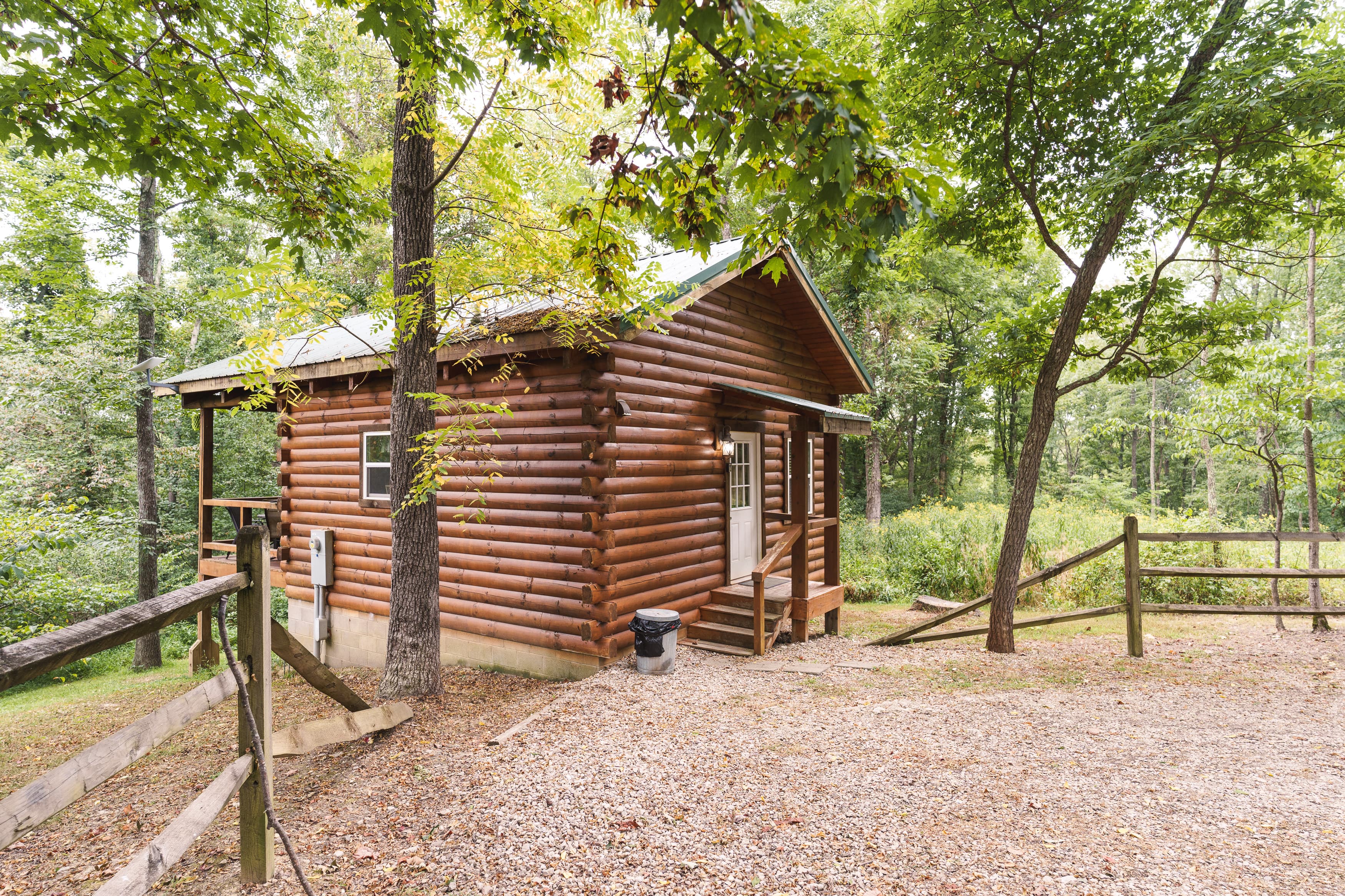 A rustic log cabin surrounded by trees and greenery.