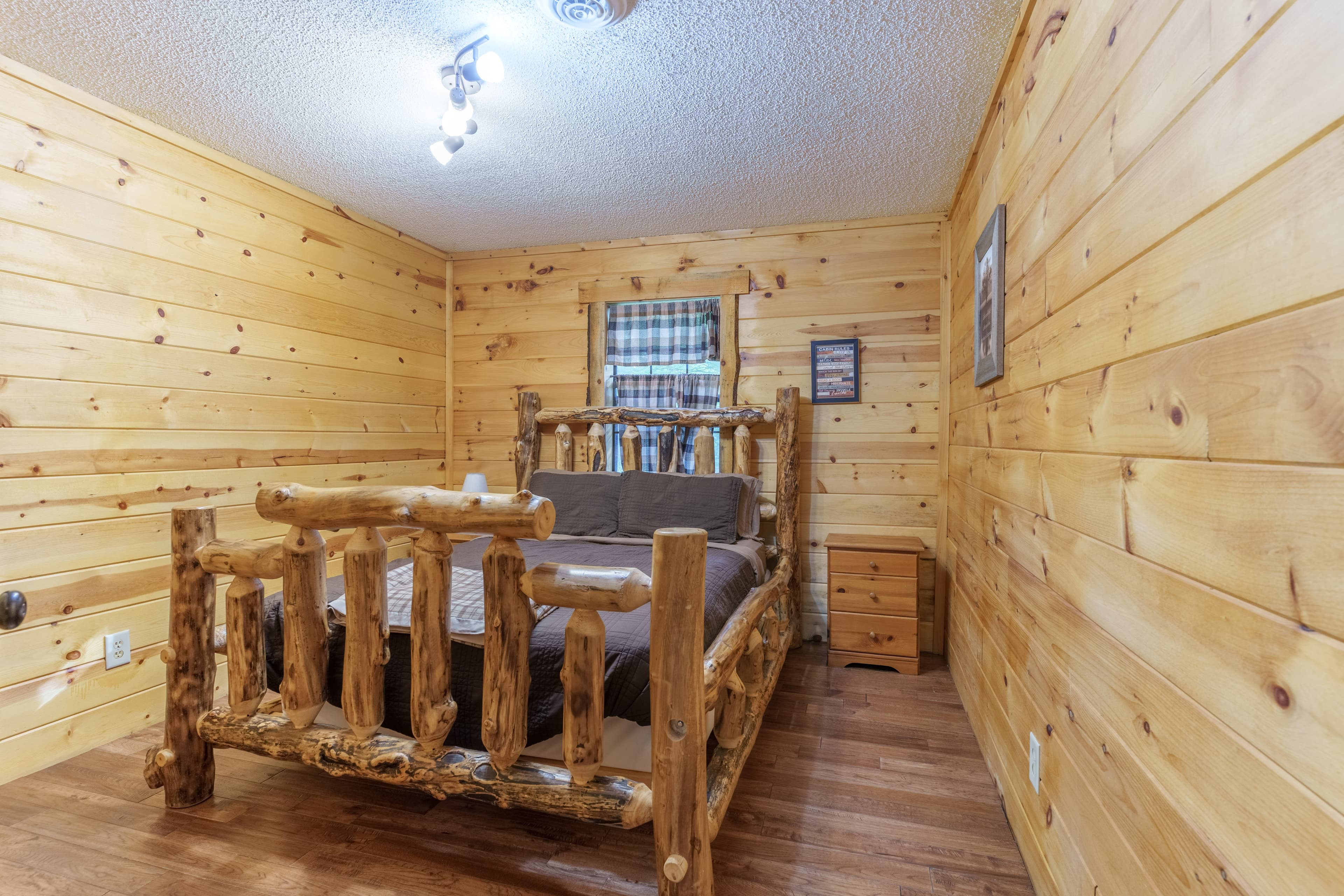 Cozy bedroom featuring a rustic wooden bed against a backdrop of light wood paneling.