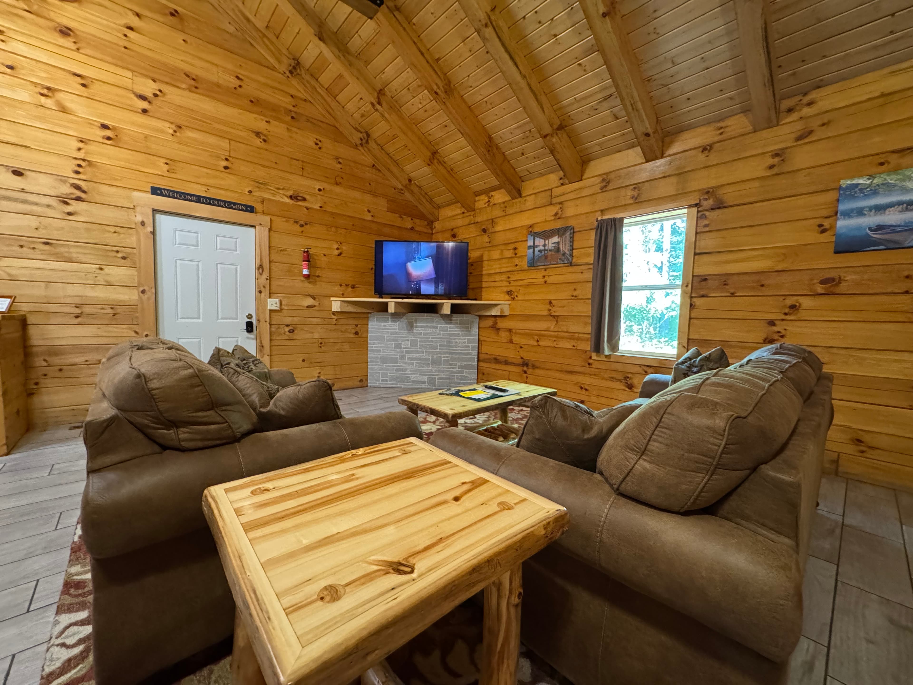 Cozy wooden cabin interior with a television, comfortable couches, and a rustic coffee table.