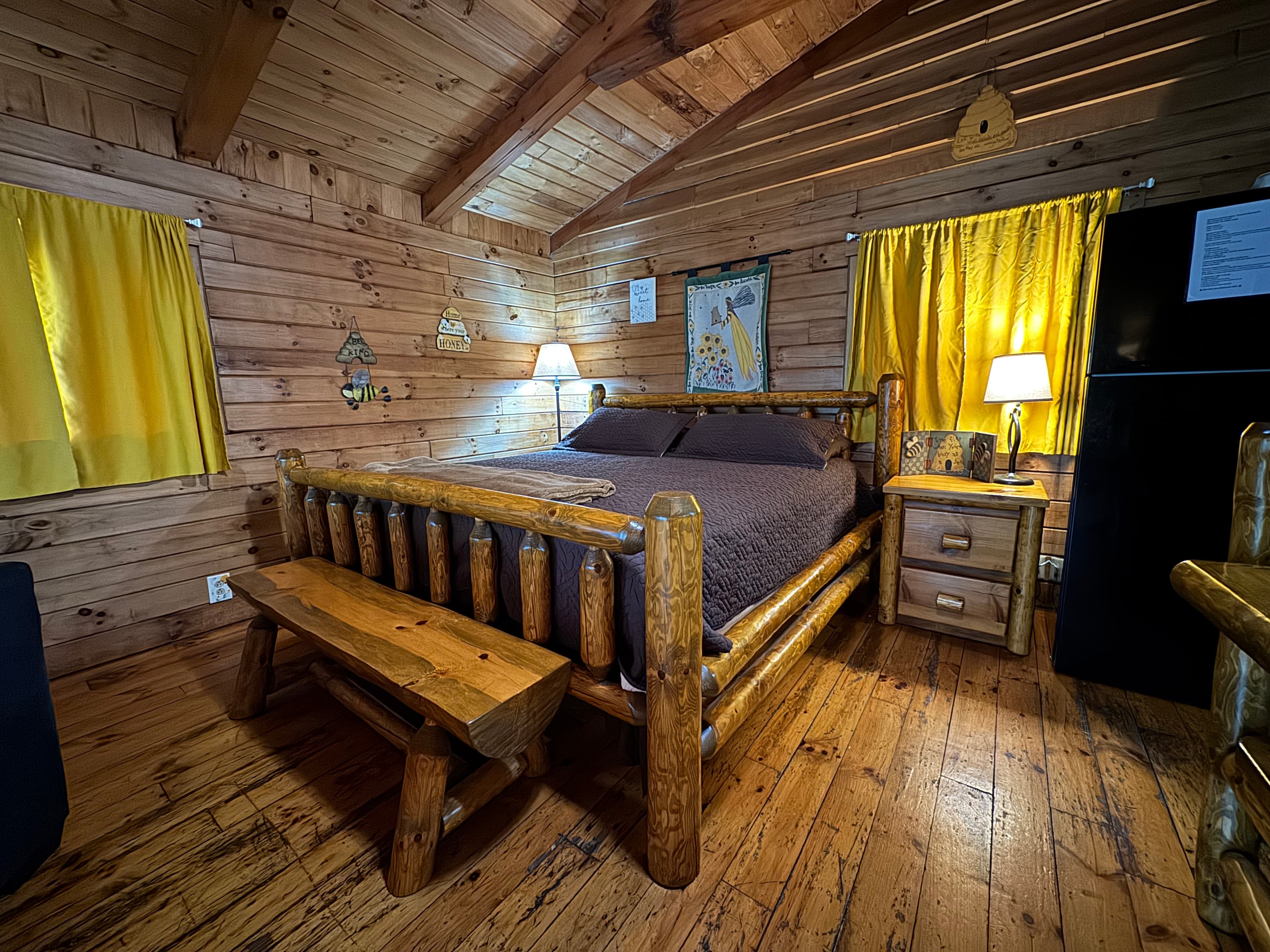 Cozy rustic bedroom with wooden furnishings, yellow curtains, and warm lighting.