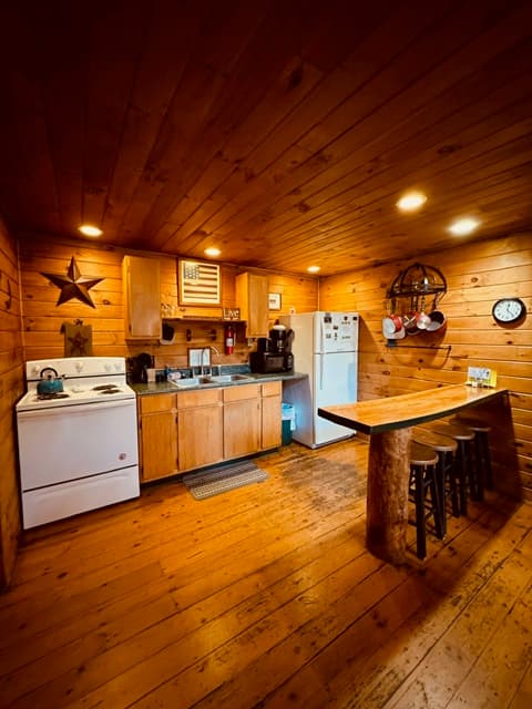 Cozy wooden kitchen with a stove, refrigerator, and a rustic dining table.