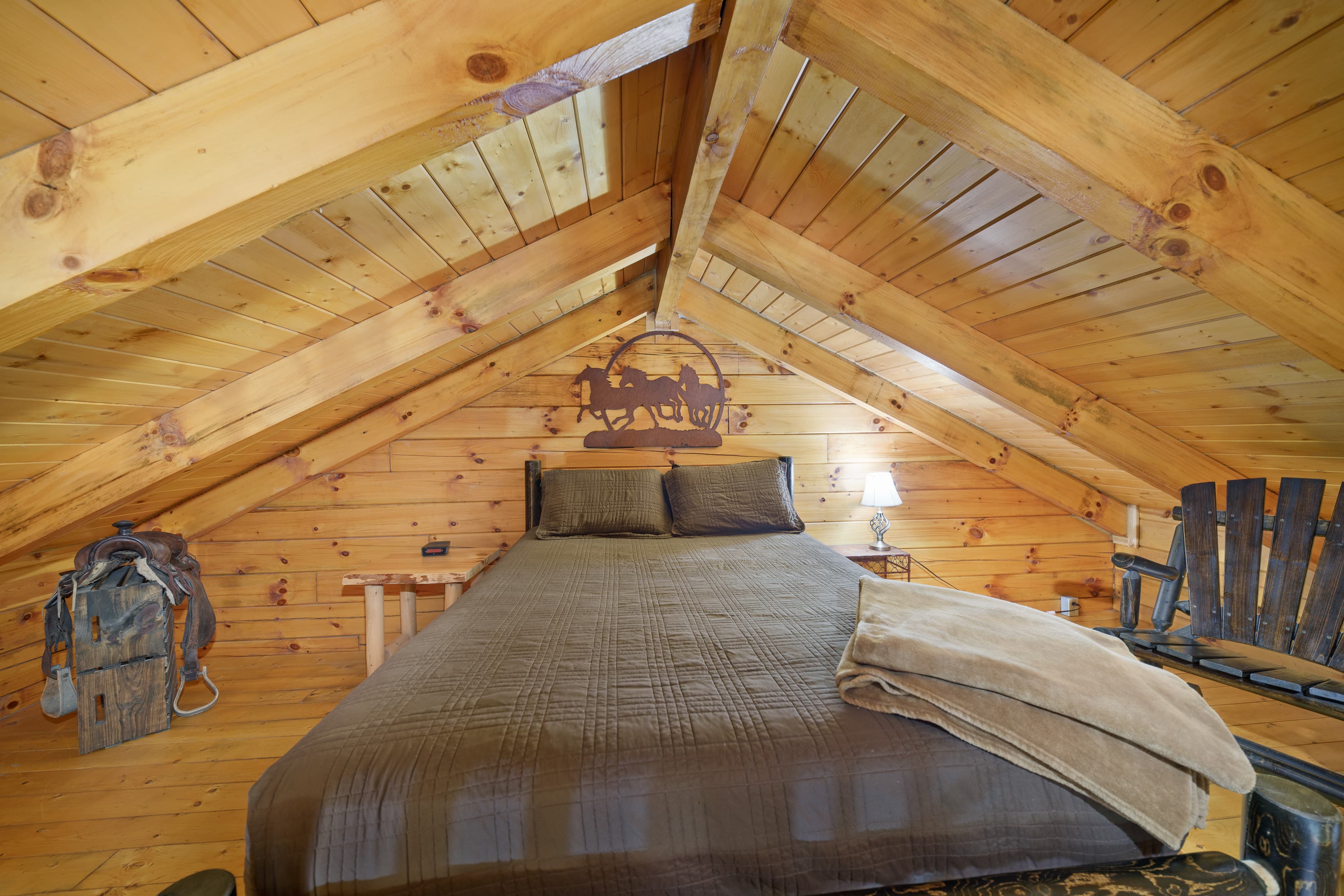 Cozy attic bedroom with wooden beams, a large bed, and rustic decor.