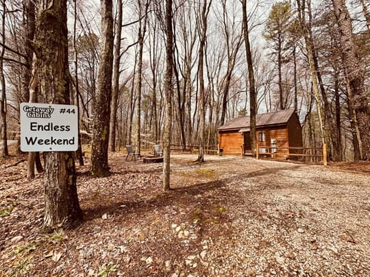 A rustic wooden cabin surrounded by trees with a sign reading "Endless Weekend."