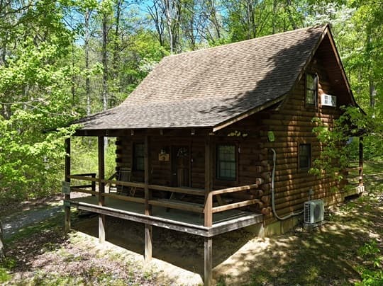 A rustic log cabin surrounded by lush greenery and trees.