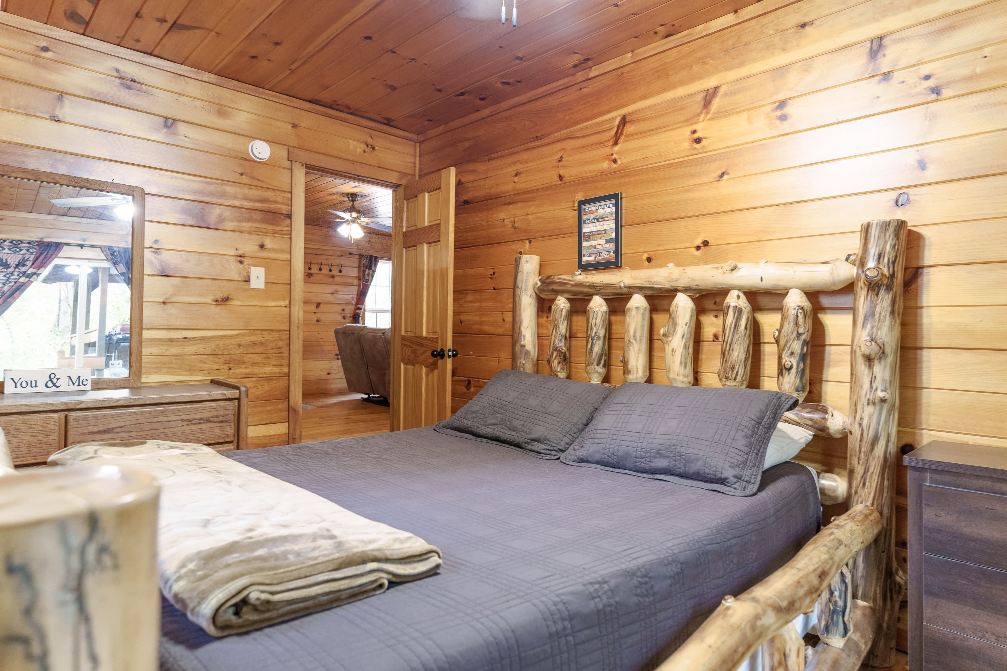 A cozy wooden bedroom featuring a log bed, gray bedding, and a rustic atmosphere.