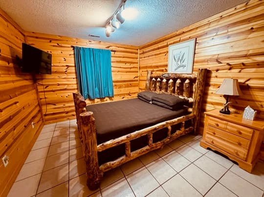 A rustic bedroom featuring a log bed, wooden walls, and a comfortable ambiance.