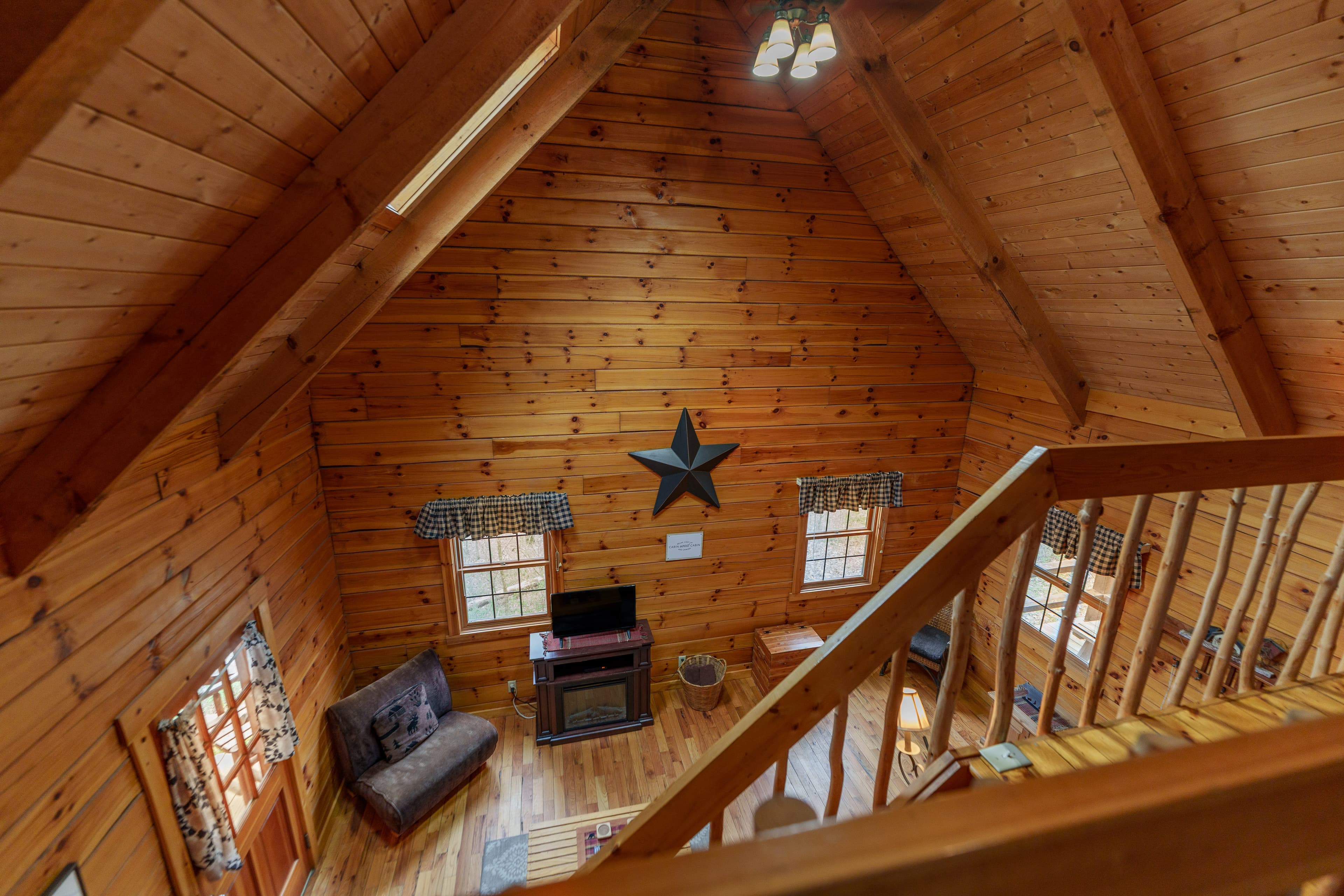 Interior view of a cozy wooden cabin with a star decoration and large windows.