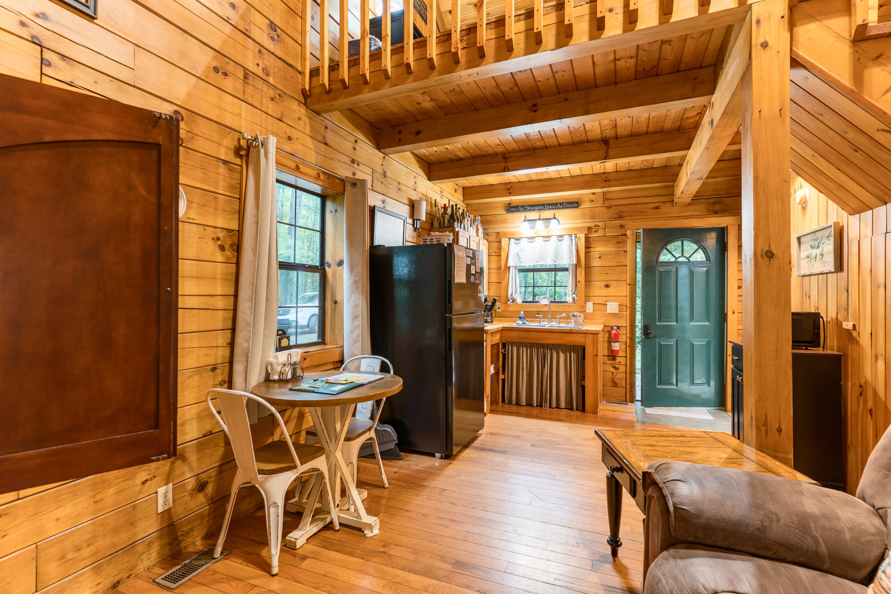 Cozy wooden interior of a cabin featuring a kitchenette, dining area, and a living space.