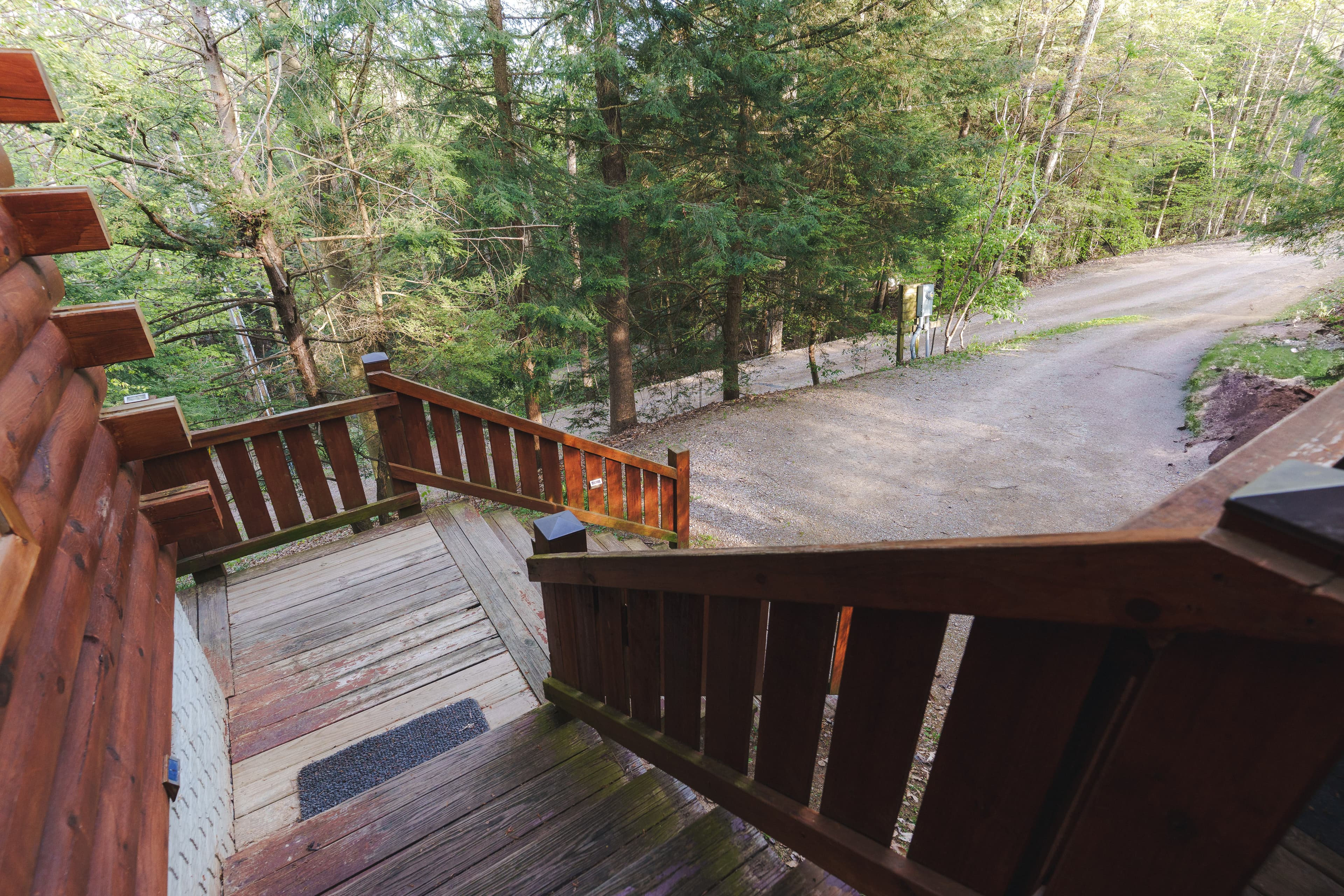 Staircase leading down to a gravel road surrounded by trees.