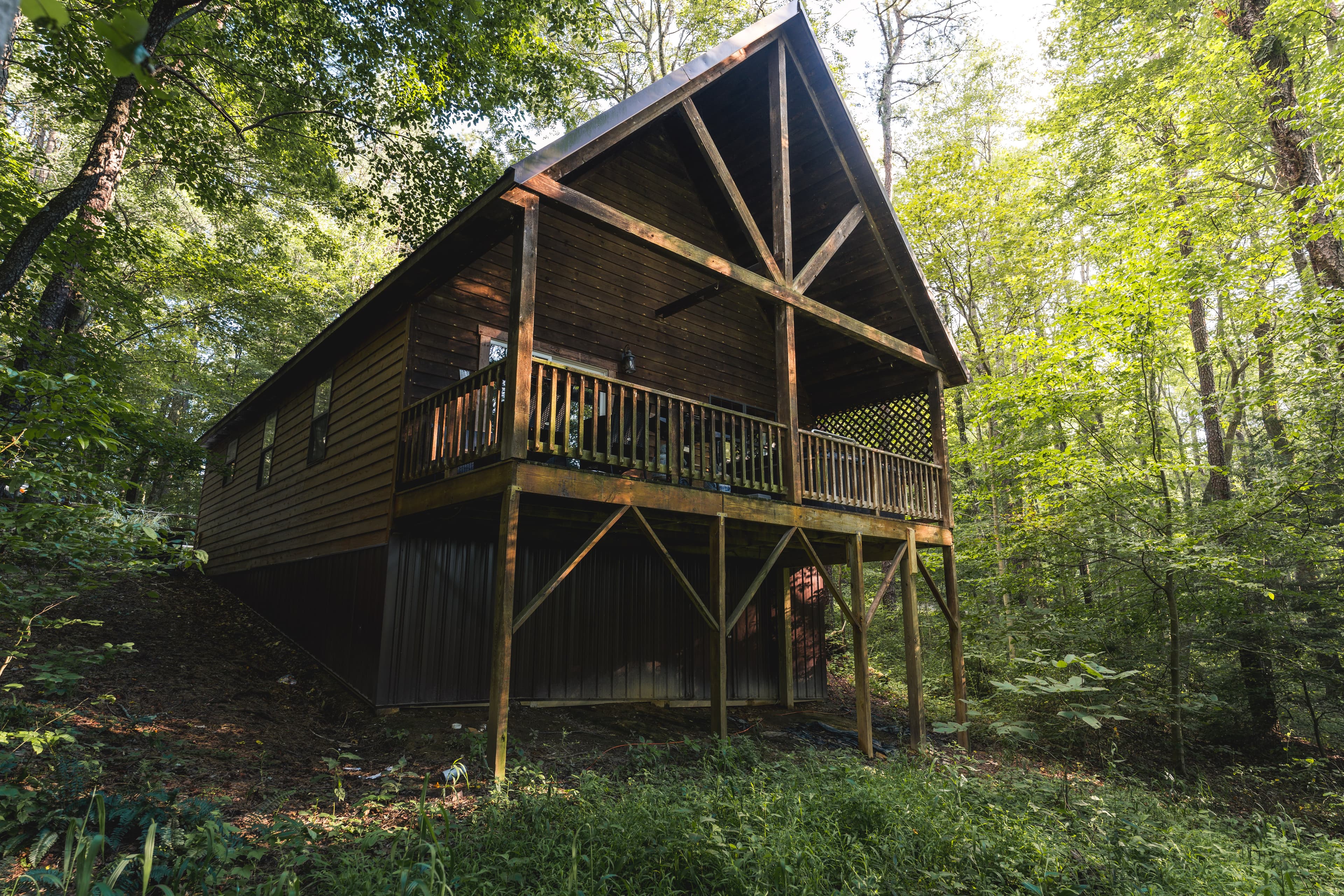 A wooden cabin on stilts surrounded by lush greenery.