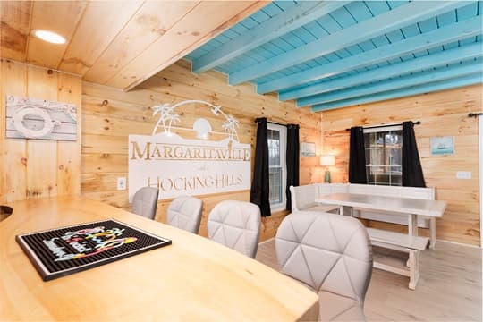 A cozy wooden interior featuring a bar area, dining table, and a sign for Margaritaville Hocking Hills.