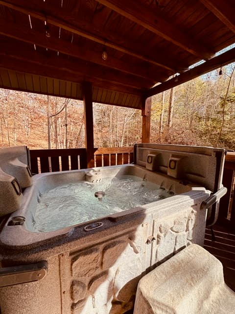 A hot tub with bubbling water on a wooden deck surrounded by trees.