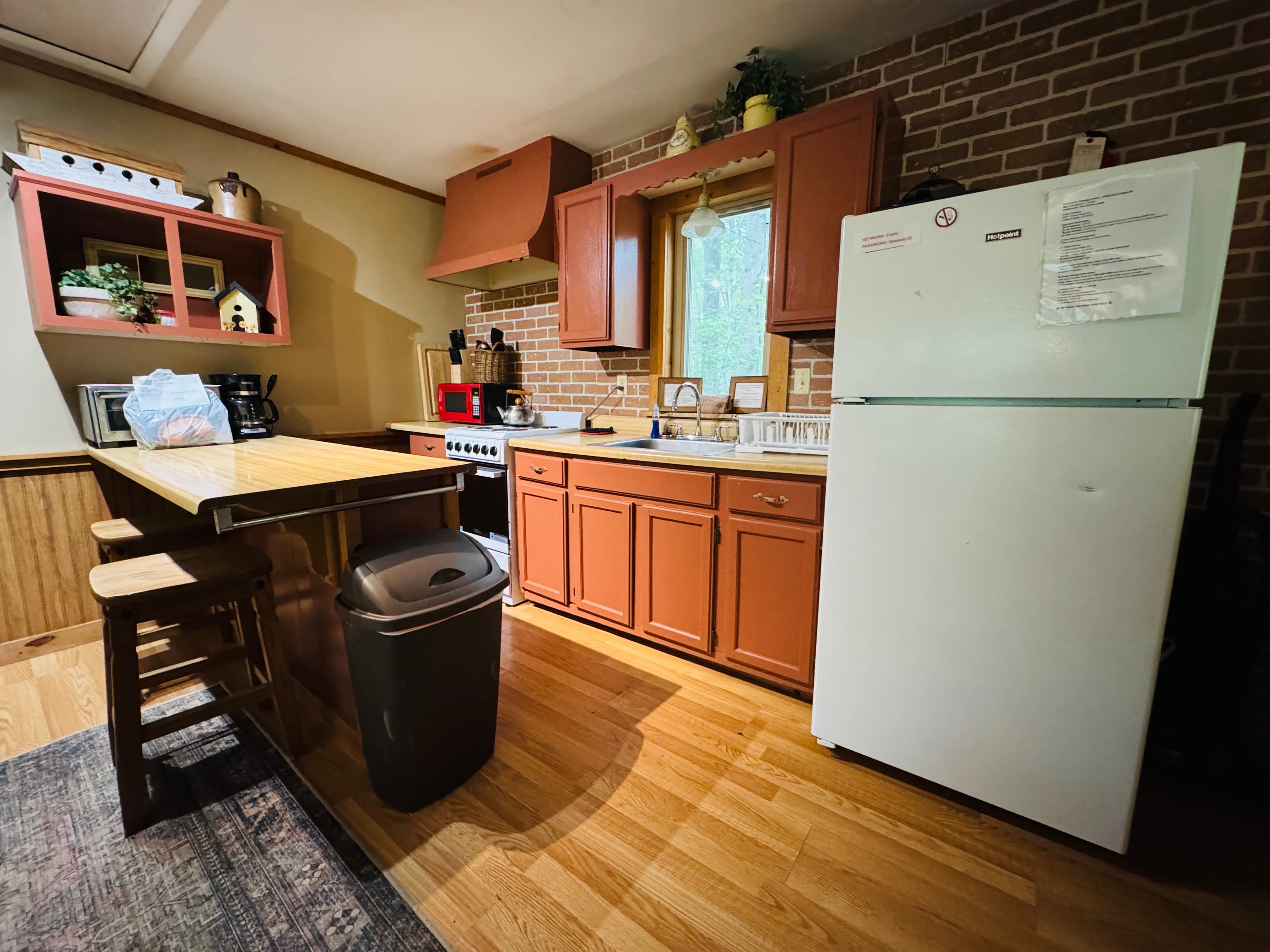 A cozy kitchen featuring wooden cabinetry, a white refrigerator, and a countertop with stools.