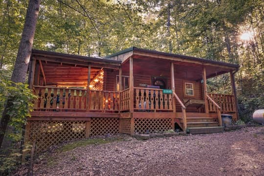 A rustic wooden cabin nestled in a wooded area with a welcoming front porch.
