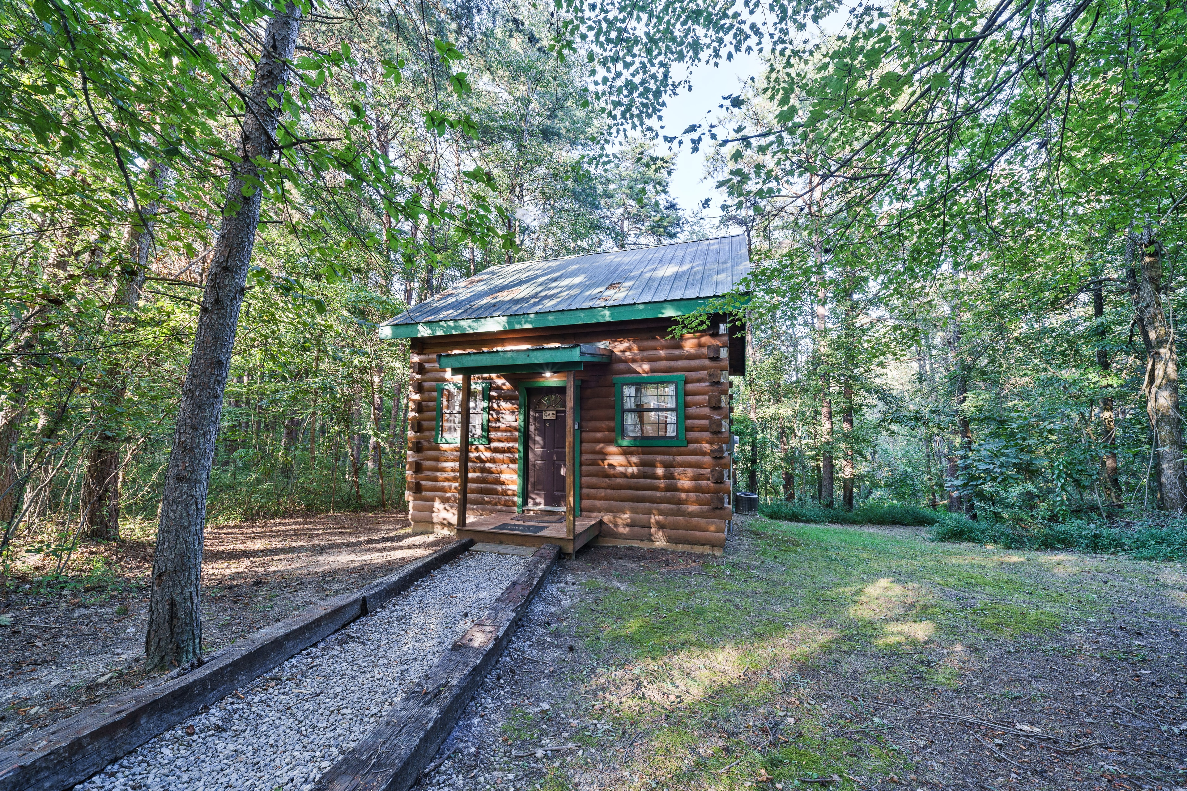 A small log cabin surrounded by lush greenery and trees.