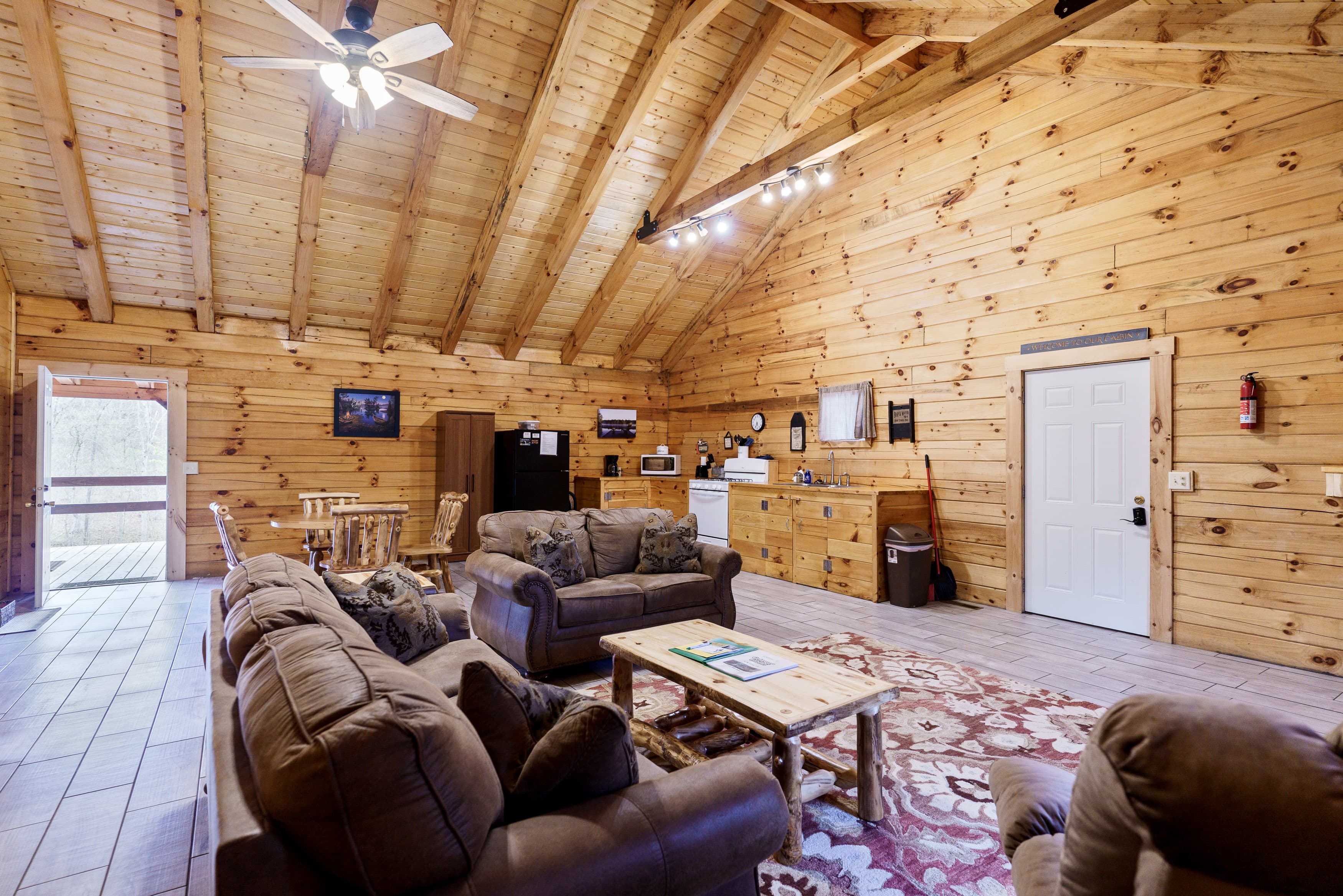 Cozy log cabin interior featuring wooden walls, comfortable seating, and a kitchen area.