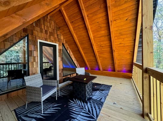 A cozy outdoor seating area with modern chairs and a table, nestled beneath a wooden, angled roof.
